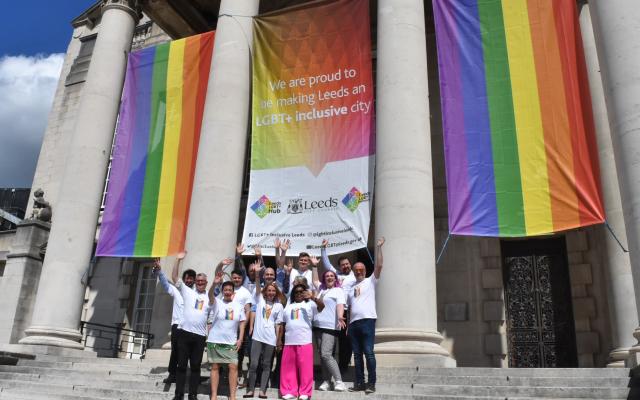 Members of Leeds City Council wearing pride t-shirts in-front of pride banners outside Leeds town hall.
