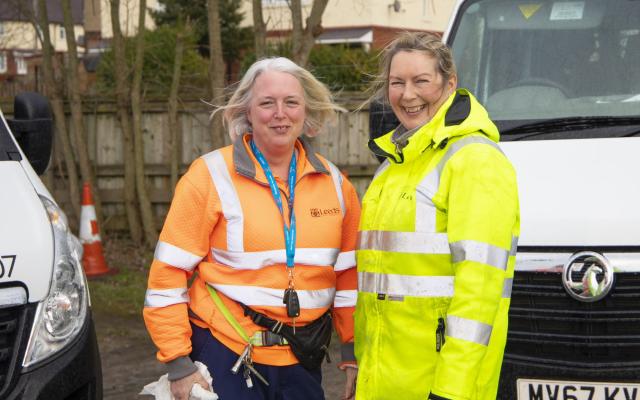 Two female Leeds city council staff members wearing hi-vis clothing smiling