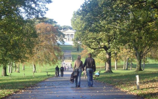 A view of Roundhay Park in Leeds shows people walking down an avenue towards a grand building with pillars